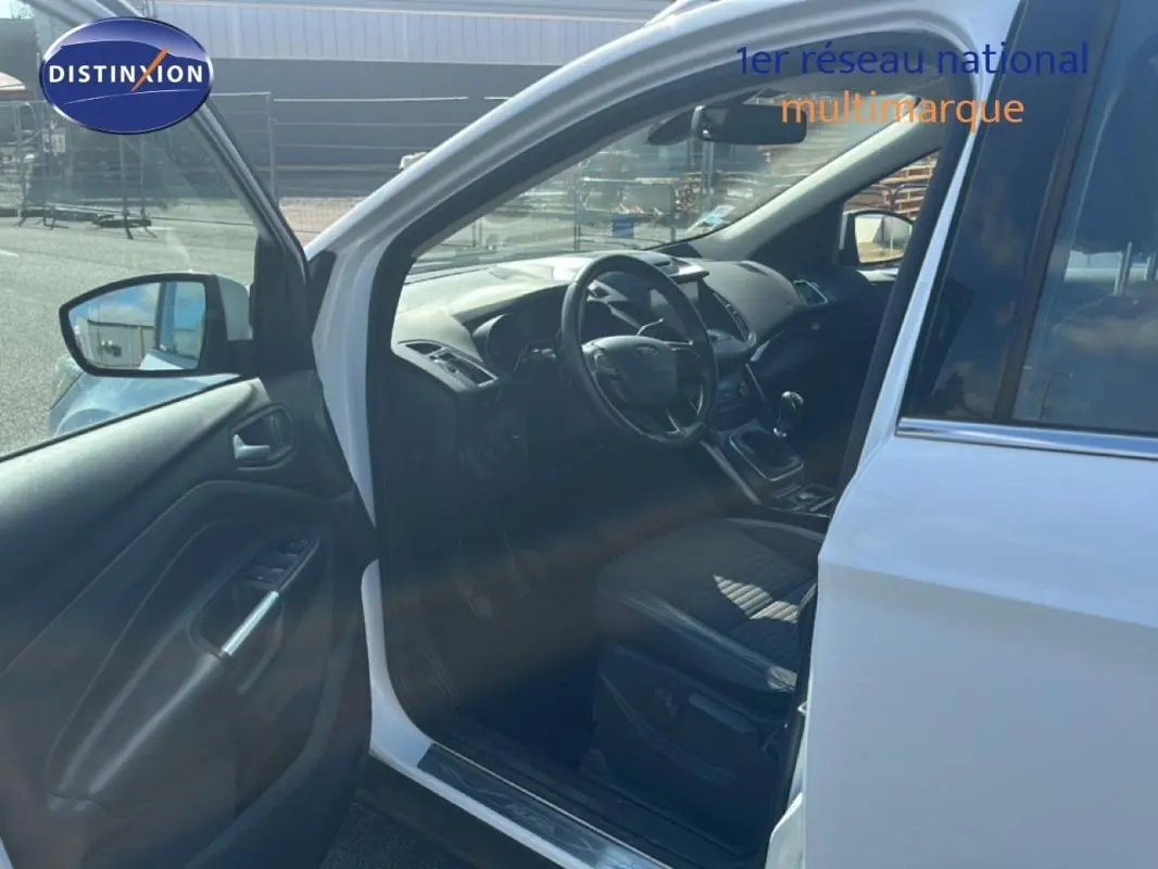 Vue côté conducteur d’un Ford Kuga blanc 2019 avec porte ouverte, montrant l’intérieur et le volant cuir.