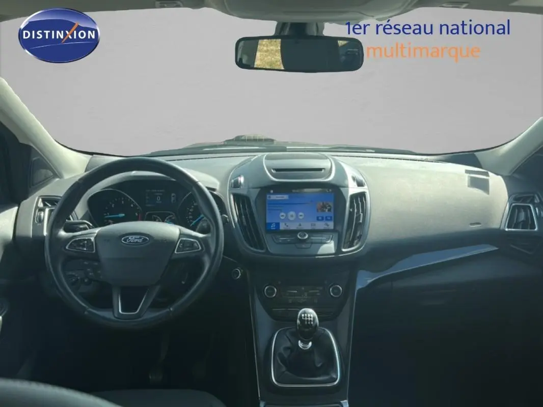 Vue intérieure avant du Ford Kuga 2019, tableau de bord noir avec volant cuir et écran tactile central.