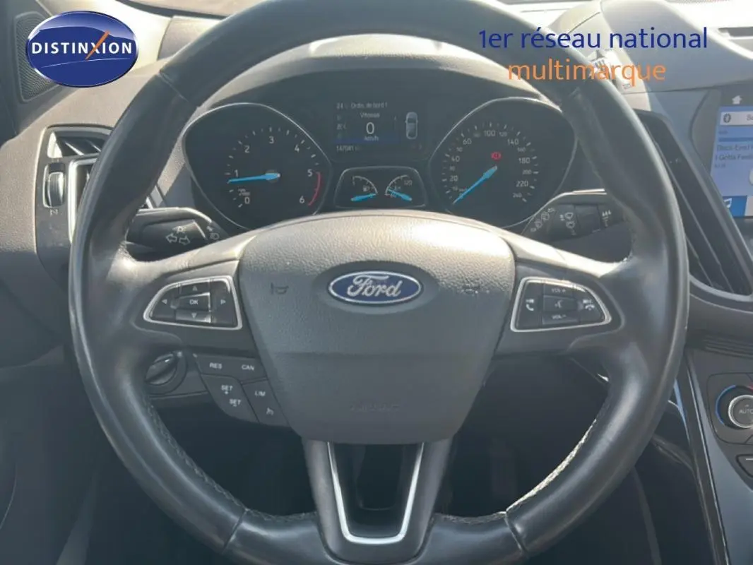 Vue rapprochée du volant cuir noir du Ford Kuga 2019 avec commandes intégrées et tableau de bord digital.