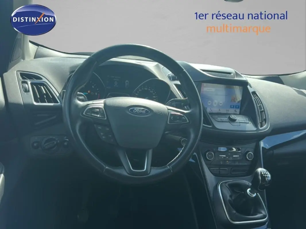 Vue intérieure du tableau de bord et volant cuir noir d’un Ford Kuga 2019 avec écran tactile et boîte manuelle.