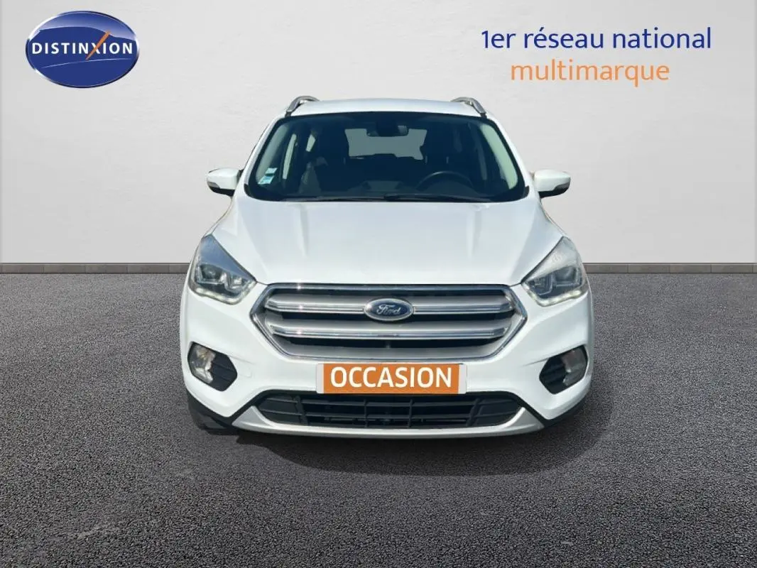 Vue frontale d'un Ford Kuga blanc 2019 avec calandre chromée et phares halogènes allumés.