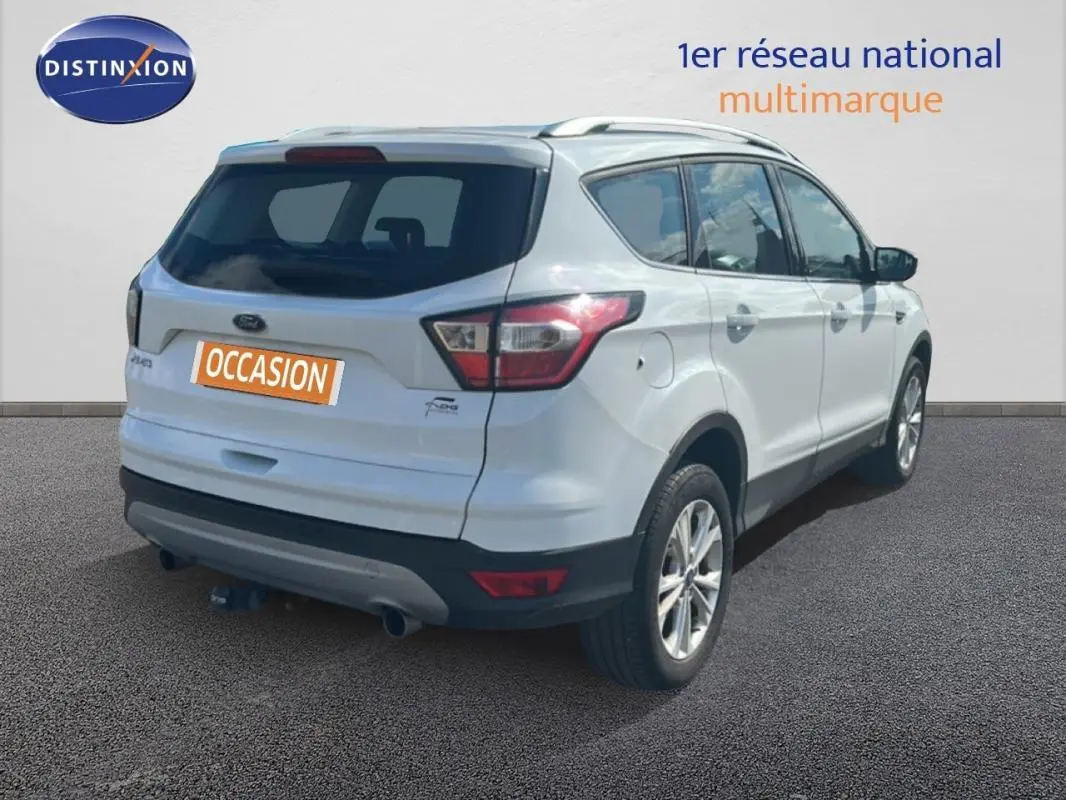 Vue 3/4 arrière droite d'un Ford Kuga blanc 2019 avec barres de toit et jantes alliage 17 pouces.