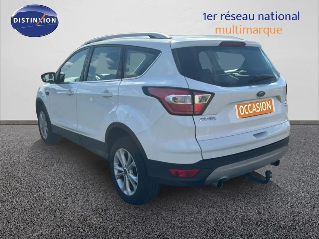 Vue 3/4 arrière droite d'un Ford Kuga blanc 2019 avec barres de toit et jantes alliage 17 pouces.
