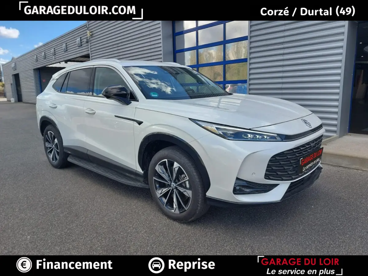 MG Motor EHS hybride rechargeable blanc, vue 3/4 avant droit devant un bâtiment industriel.