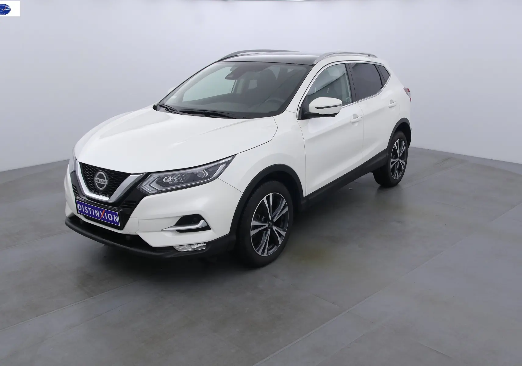 Nissan Qashqai blanc lunaire métal vu en 3/4 avant droit dans un studio lumineux avec jantes alliage noires.