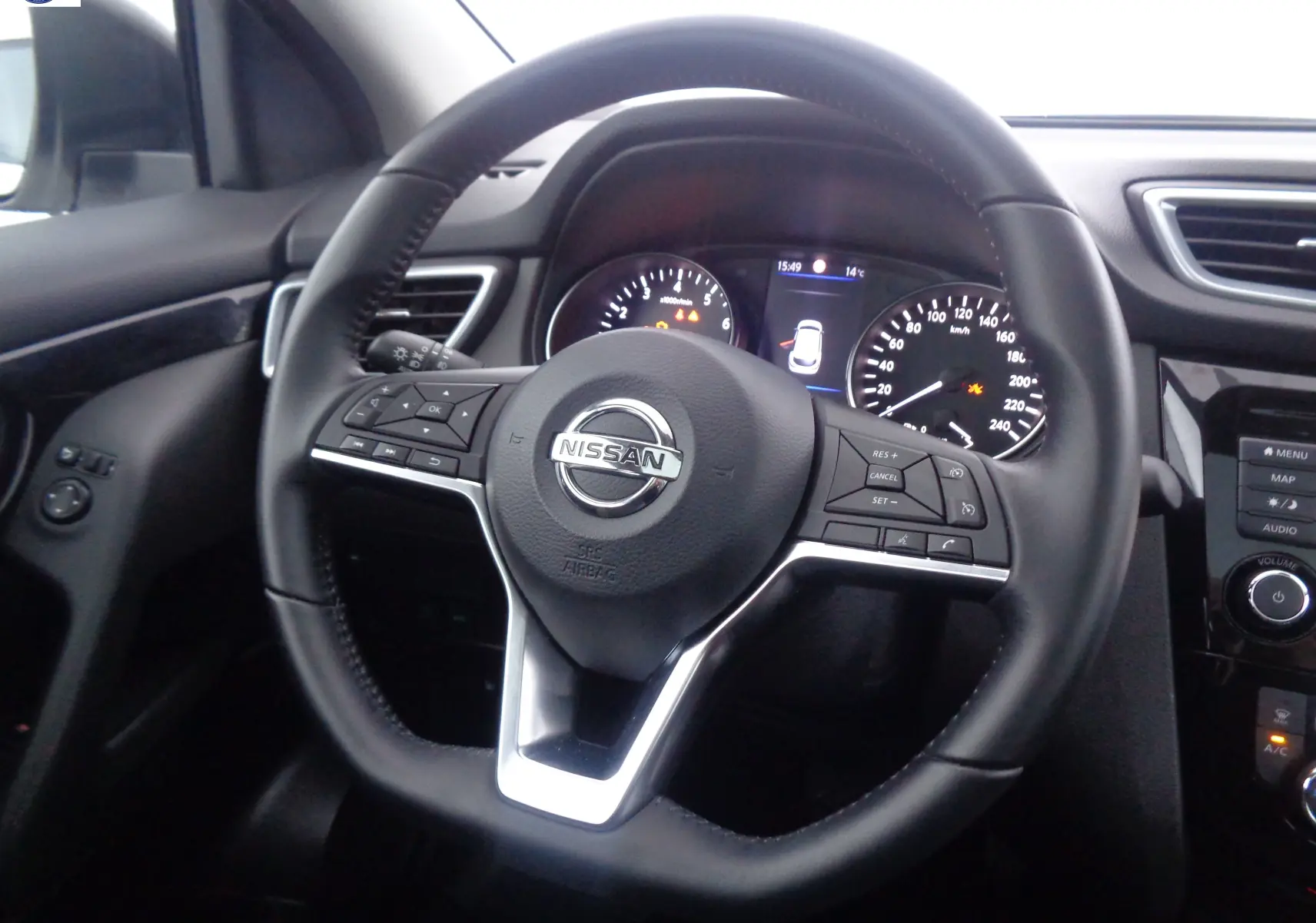 Vue rapprochée du volant noir du Nissan Qashqai 2020 avec commandes intégrées et tableau de bord éclairé.