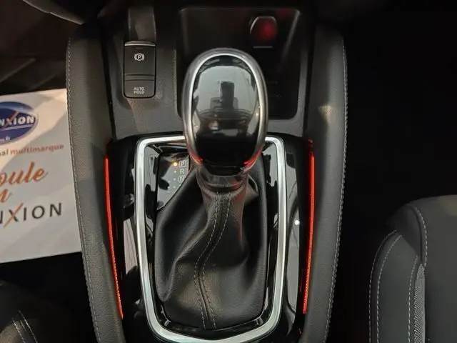 Le levier de vitesse automatique noir du Nissan Qashqai 2020, vu de dessus avec éclairage ambiant rouge.