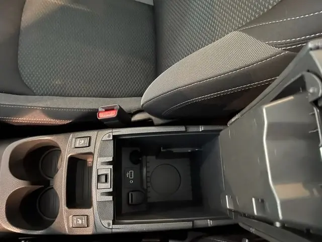 Vue rapprochée de la console centrale ouverte du Nissan Qashqai blanc lunaire, montrant les ports USB et prise 12V.