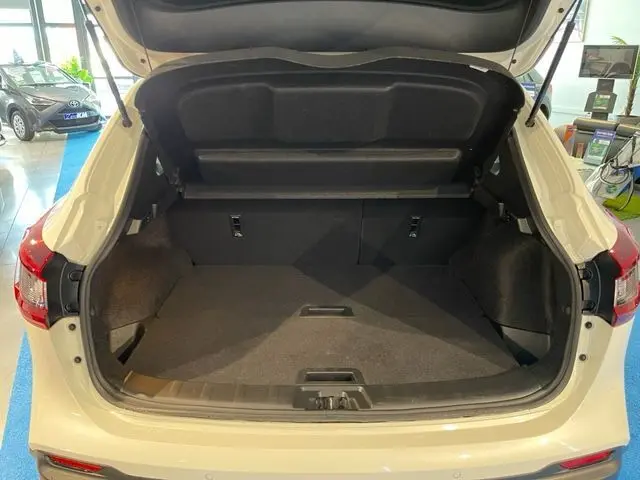 Coffre ouvert vu de l'arrière d'un Nissan Qashqai blanc lunaire métal, intérieur spacieux et propre visible.