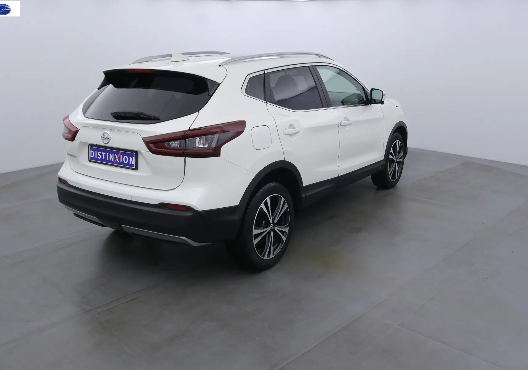 Vue 3/4 arrière droite du Nissan Qashqai blanc lunaire avec vitres teintées et jantes alliage noires.