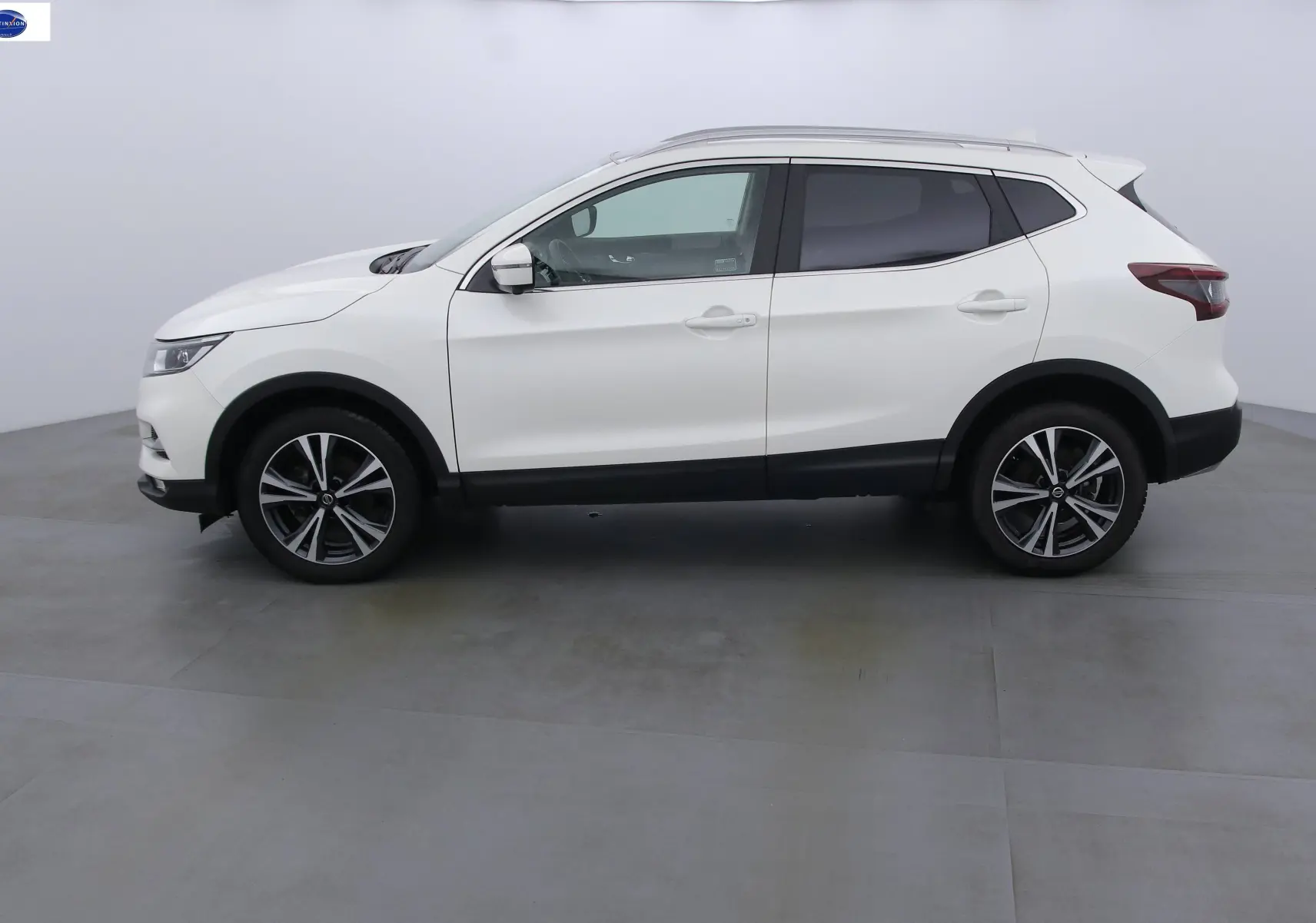 Profil côté gauche d'un Nissan Qashqai blanc lunaire métal de 2020 avec jantes alliage et vitres teintées.