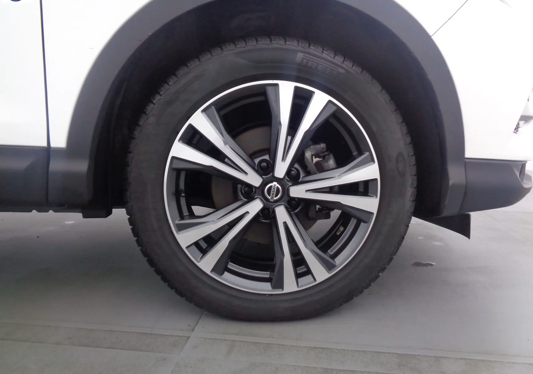 Gros plan sur la roue avant droite du Nissan Qashqai blanc lunaire métal, mettant en valeur la jante alliage moderne.