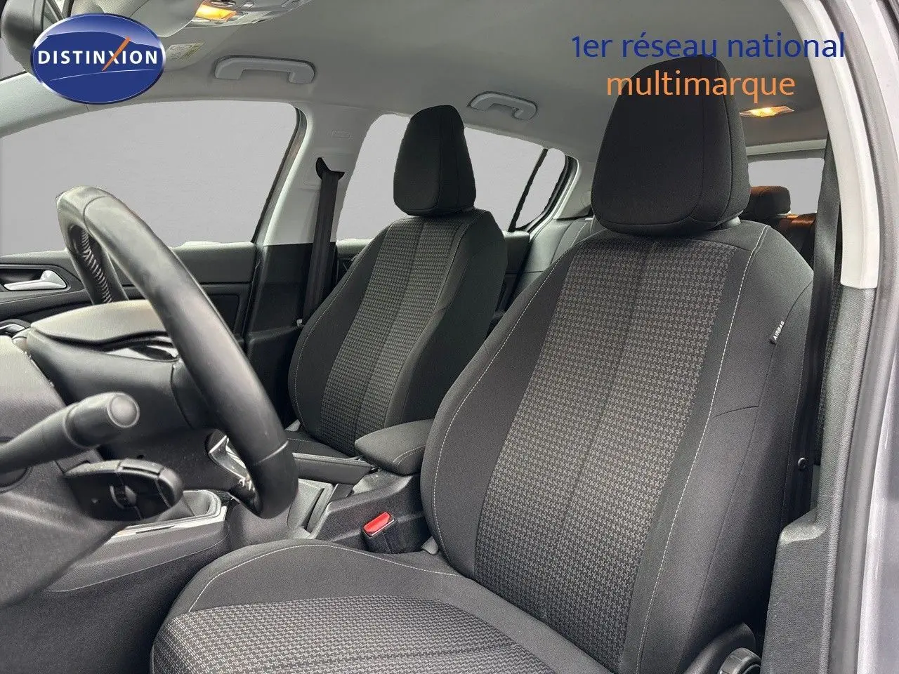 Intérieur de la Peugeot 308 2019, vue côté conducteur, sièges tissu noir avec motifs gris et volant visible.