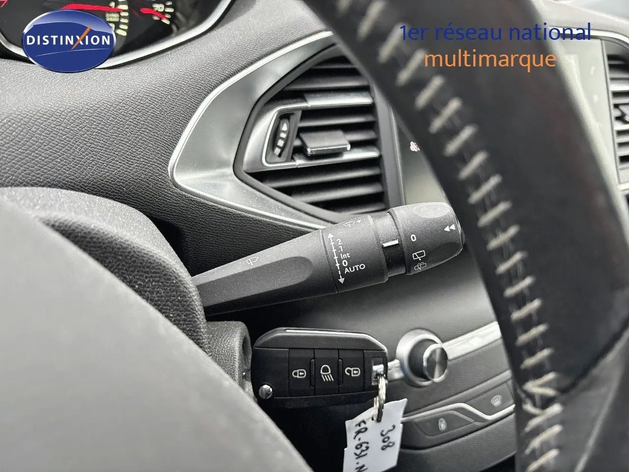 Gros plan sur la commande d’essuie-glace et la clé insérée dans le contact d’une Peugeot 308 gris Artense de 2019.