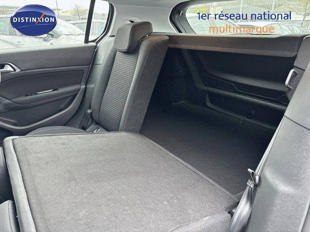 Vue intérieure arrière droite de la Peugeot 308 gris Artense avec siège rabattable et espace de coffre visible.