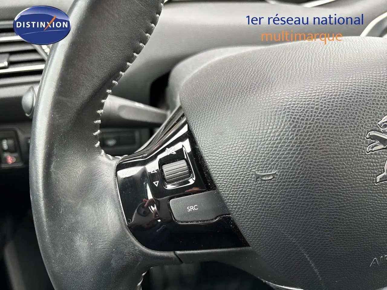 Gros plan sur le volant en cuir noir avec commandes intégrées d'une Peugeot 308 gris Artense de 2019.