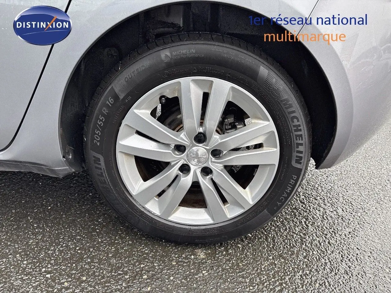 Gros plan sur la roue avant droite d'une Peugeot 308 gris Artense avec jante alliage 16 pouces et pneu Michelin.