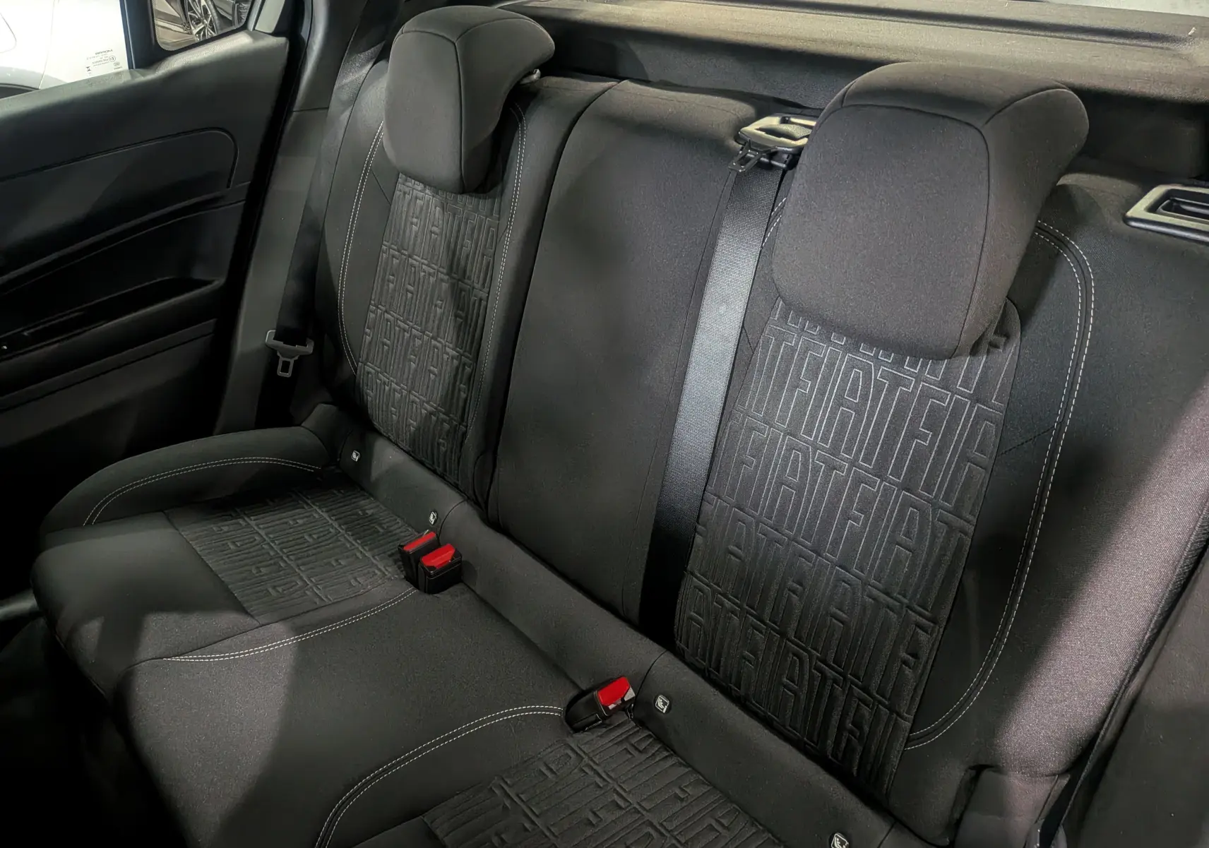 Vue rapprochée des sièges arrière noirs avec motifs FIAT en tissu dans une Fiat 600 1.2 Hybrid 2025.