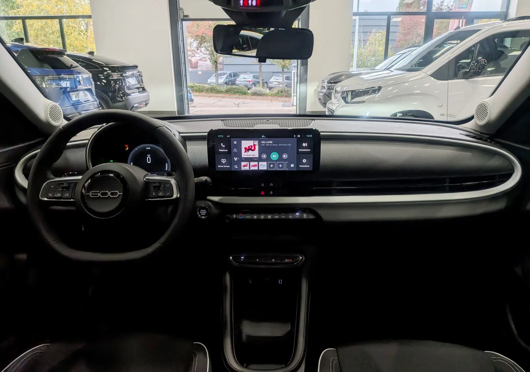 Vue intérieure frontale du tableau de bord et volant noir du FIAT 600 1.2 Hybrid 2025 avec écran tactile central lumineux.