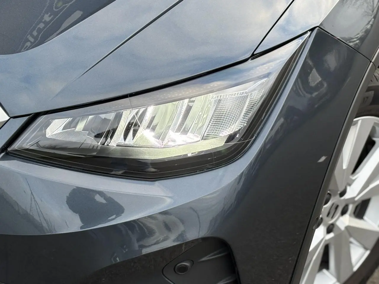 Gros plan sur le phare avant droit et la jante alliage du SEAT Arona 2025 en Gris Magnétique.