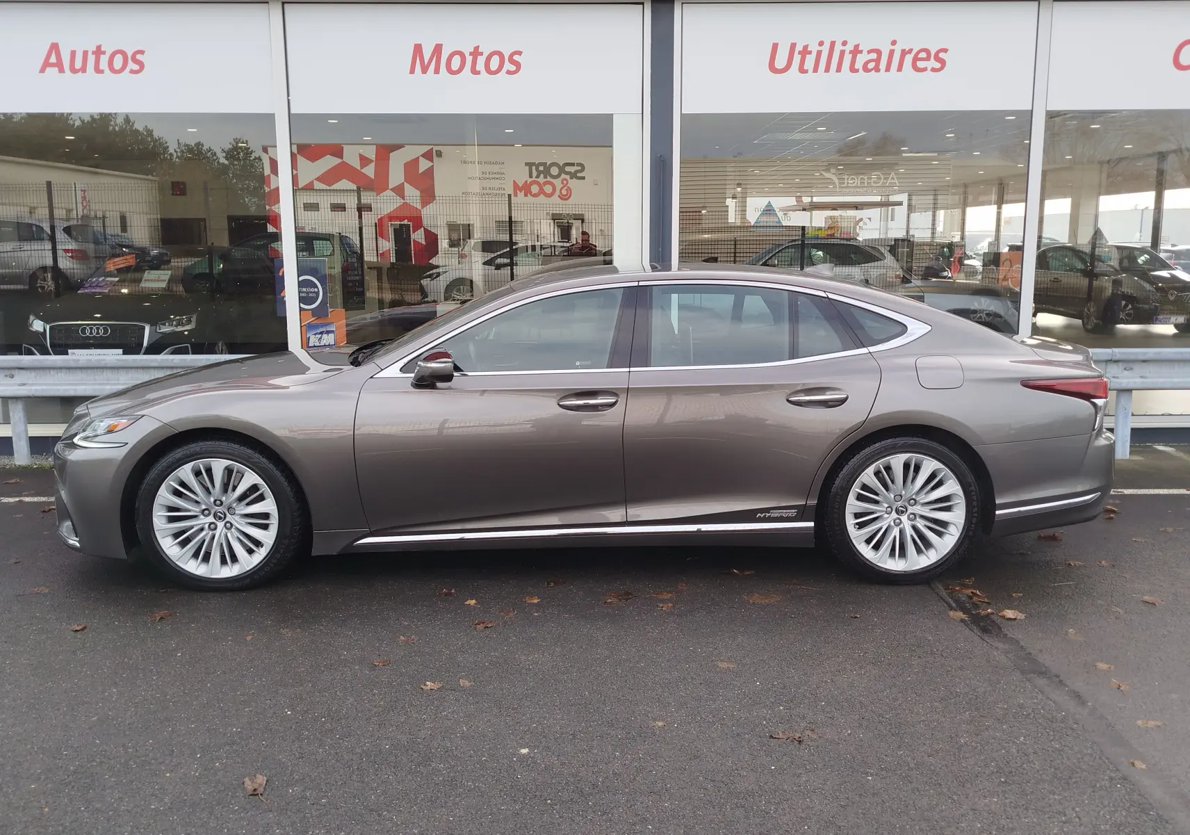 Profil latéral droit d'une Lexus LS 500H gris manganèse, berline hybride élégante avec jantes multi-branches.