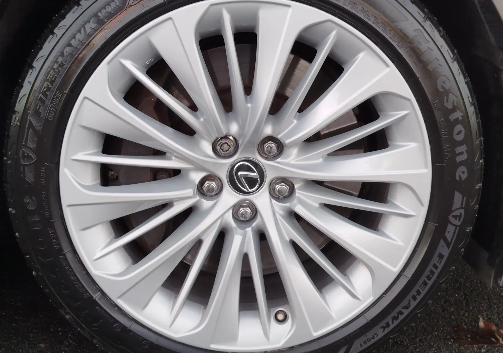 Gros plan sur la jante argentée en alliage de la Lexus LS 500H 2020 avec logo Lexus au centre et pneu Firestone.
