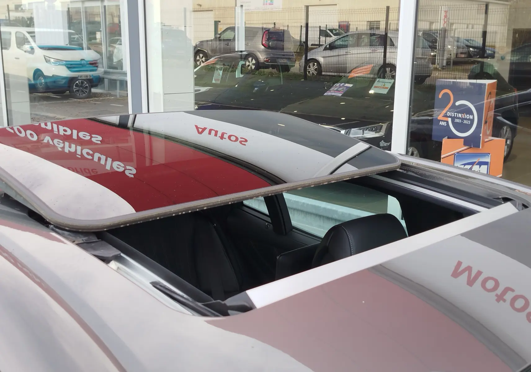 Toit ouvrant ouvert en vue plongeante sur une Lexus LS 500H gris manganèse, intérieur cuir noir visible.