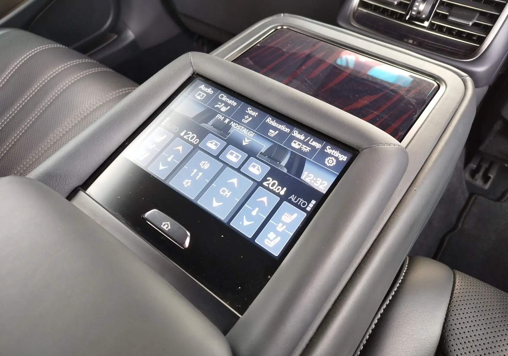 Vue rapprochée de l’écran tactile central du Lexus LS 500H 2020, avec commandes climatisation et sièges en cuir noir.