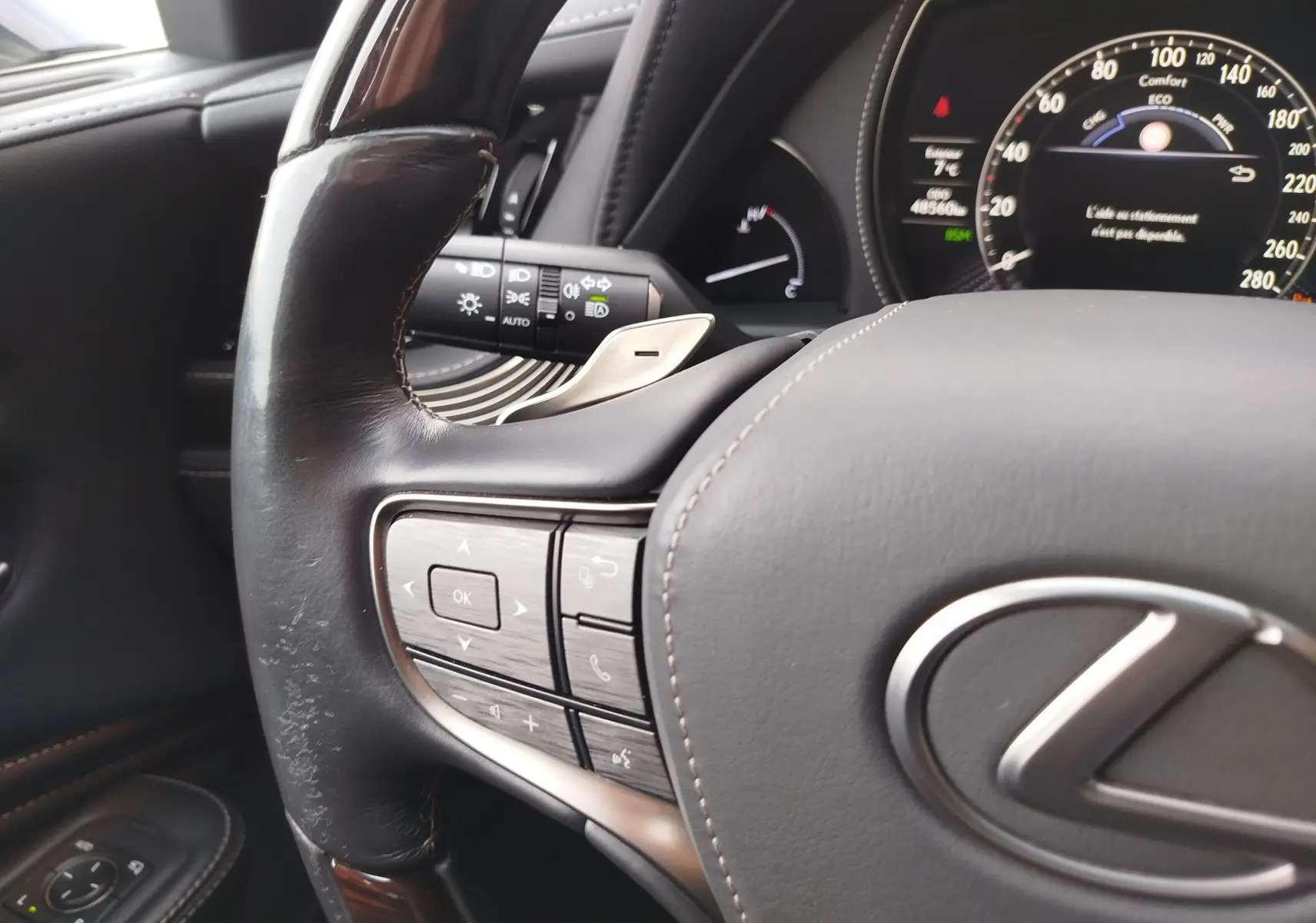 Gros plan sur le volant cuir noir de la Lexus LS 500H 2020, avec commandes intégrées et tableau de bord numérique en arrière-plan.