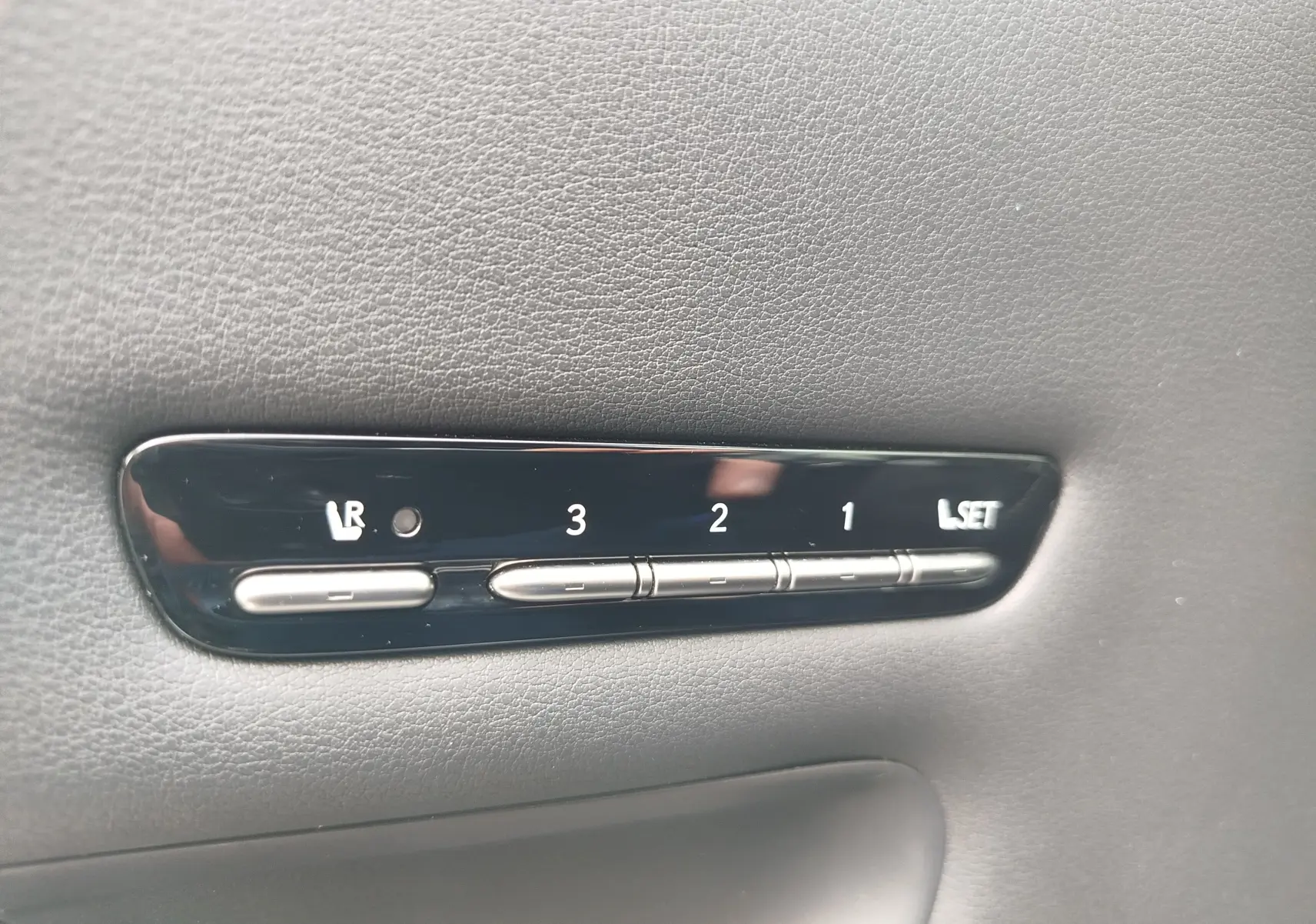 Gros plan sur les boutons de réglage mémoire des sièges en cuir noir dans une Lexus LS 500H gris manganèse.