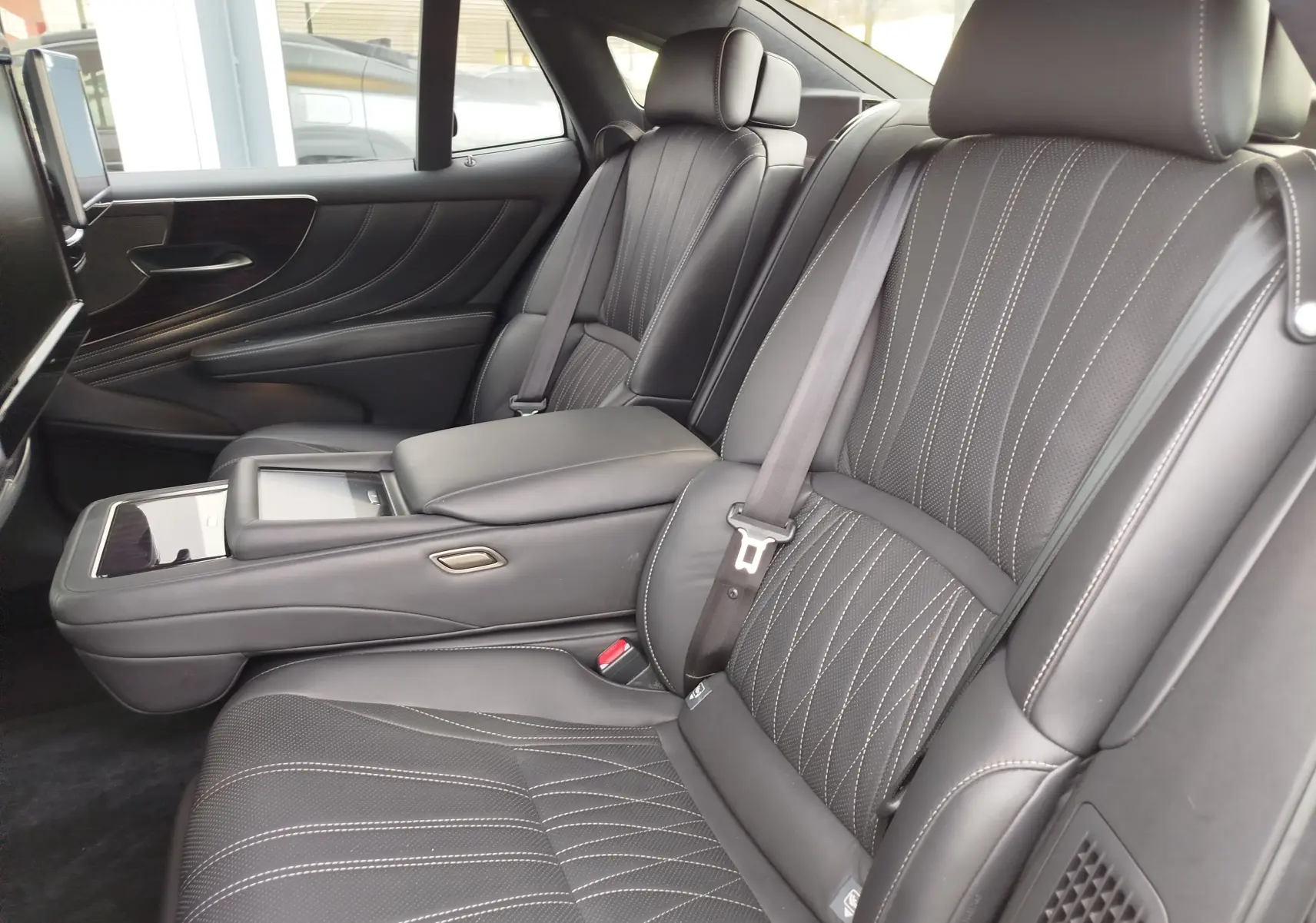 Vue intérieure latérale droite des sièges arrière en cuir noir avec surpiqûres blanches du Lexus LS 500H Executive.