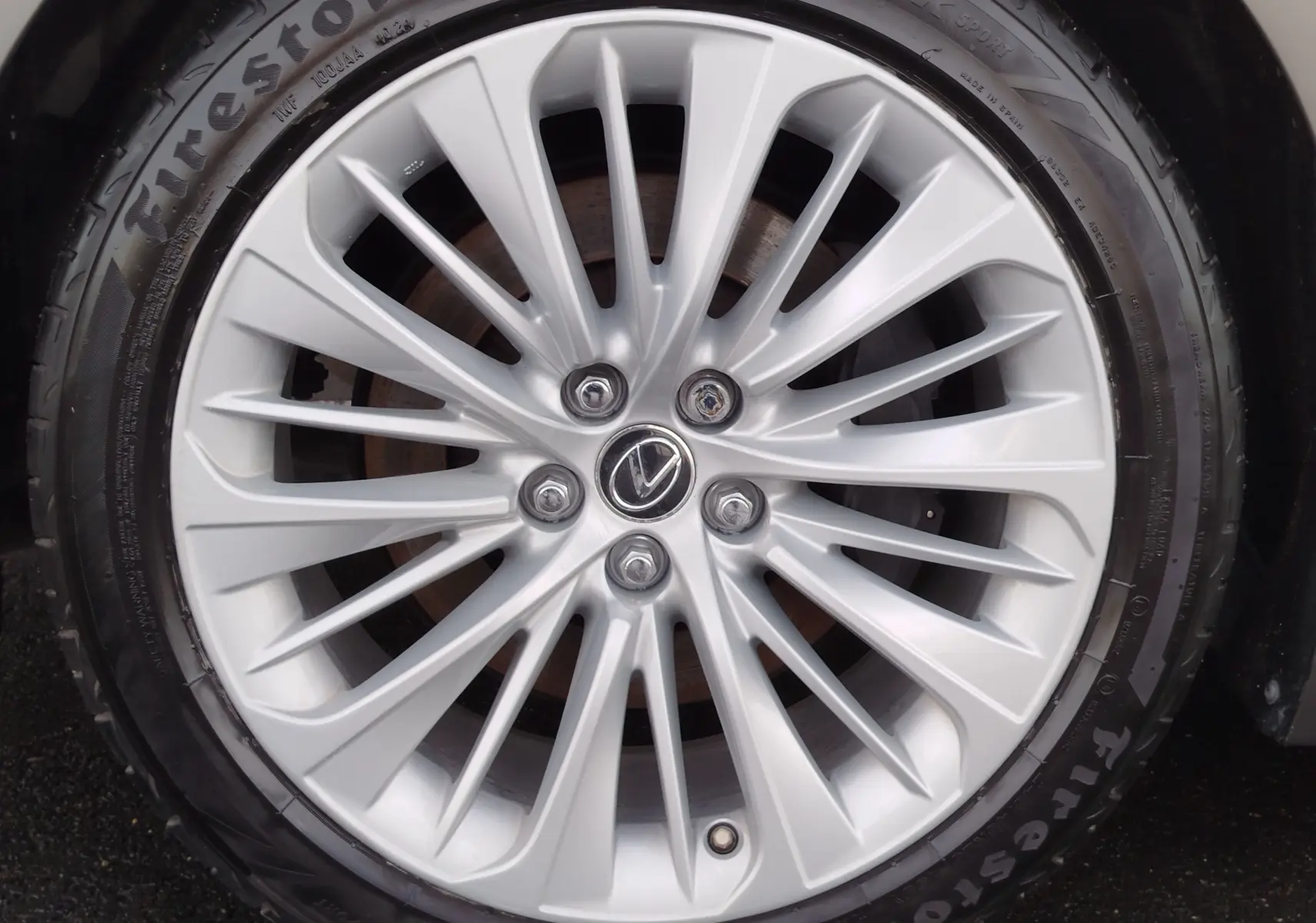 Gros plan sur la jante alliage argentée de la Lexus LS 500H 2020 avec logo Lexus au centre et pneu Firestone.