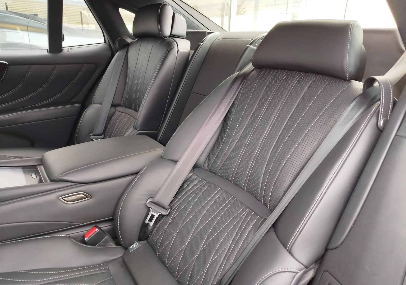 Vue intérieure rapprochée des sièges arrière en cuir noir avec surpiqûres blanches du Lexus LS 500H 2020.