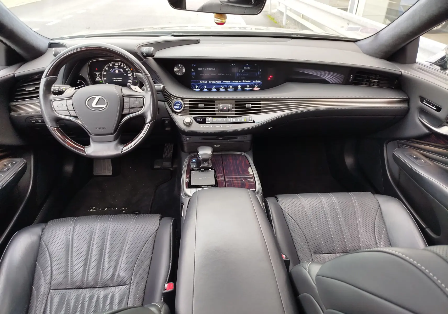 Vue intérieure avant de la Lexus LS 500H 2020, tableau de bord noir avec inserts bois et écran tactile large.
