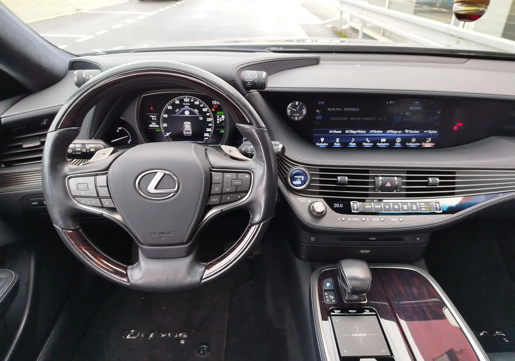 Vue intérieure du poste de conduite de la Lexus LS 500H 2020, avec volant cuir et tableau de bord digital lumineux.