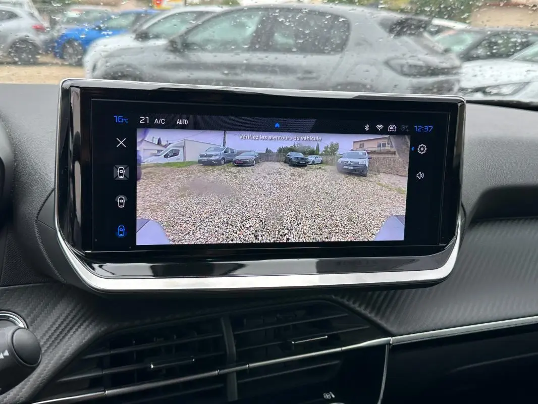 Écran tactile central du Peugeot 2008 Hybrid 145 Allure montrant la caméra de recul avec vue sur un parking gravillonné.