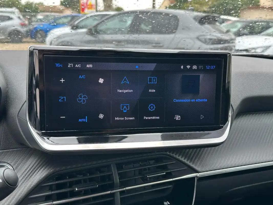 Écran tactile central du tableau de bord d’un Peugeot 2008 Hybrid gris, affichant les commandes de climatisation et navigation.