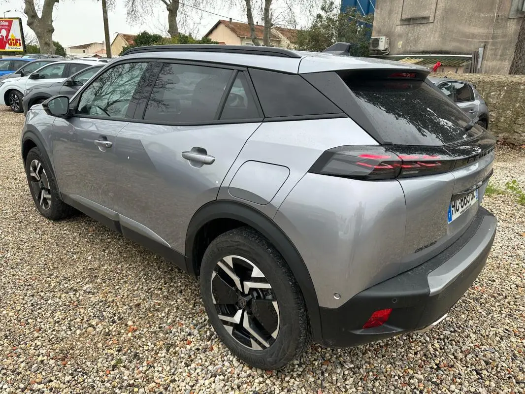 Vue 3/4 arrière droite d’un Peugeot 2008 Hybrid gris avec jantes alliage 17 pouces et toit noir.