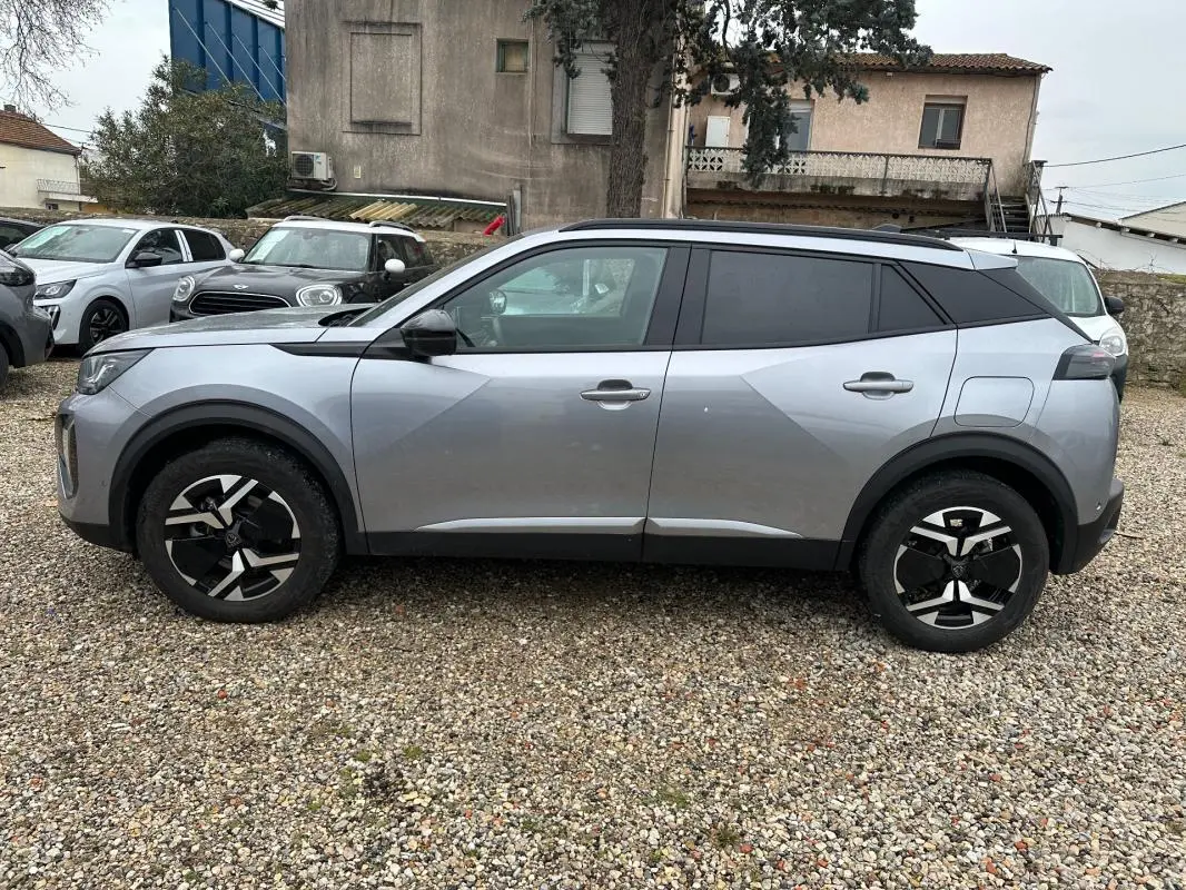 Vue de profil côté gauche d'un Peugeot 2008 Hybrid gris avec jantes alliage noires et toit noir contrasté.