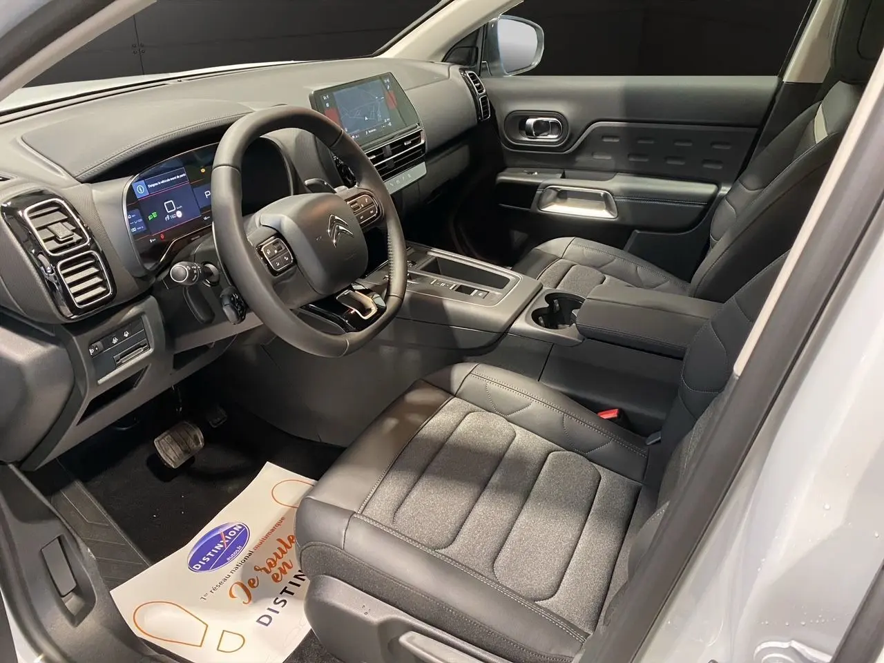 Intérieur noir du Citroën C5 Aircross 2024 vu côté conducteur, avec tableau de bord digital et sièges tissu cuir.