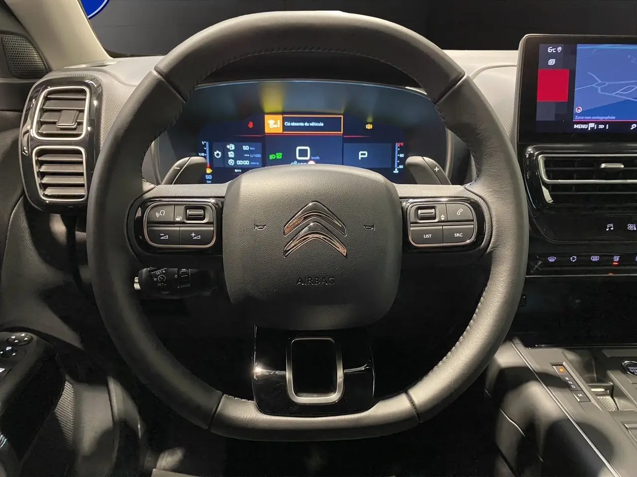 Vue rapprochée du volant cuir noir de la Citroën C5 Aircross 2024 avec tableau de bord numérique et écran tactile.