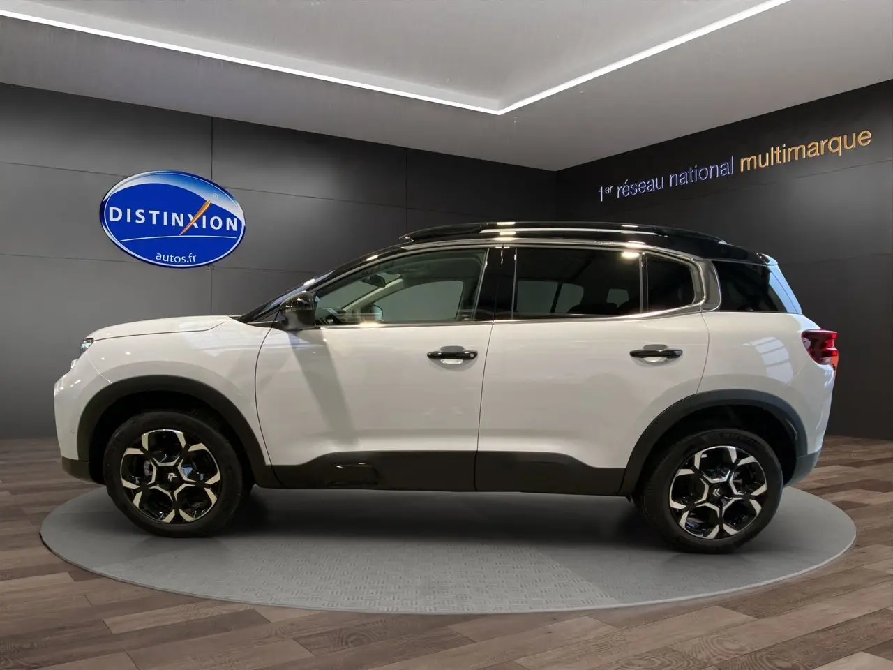 Profil côté gauche du Citroën C5 Aircross 2024 blanc et noir avec jantes noires et toit contrasté en showroom.