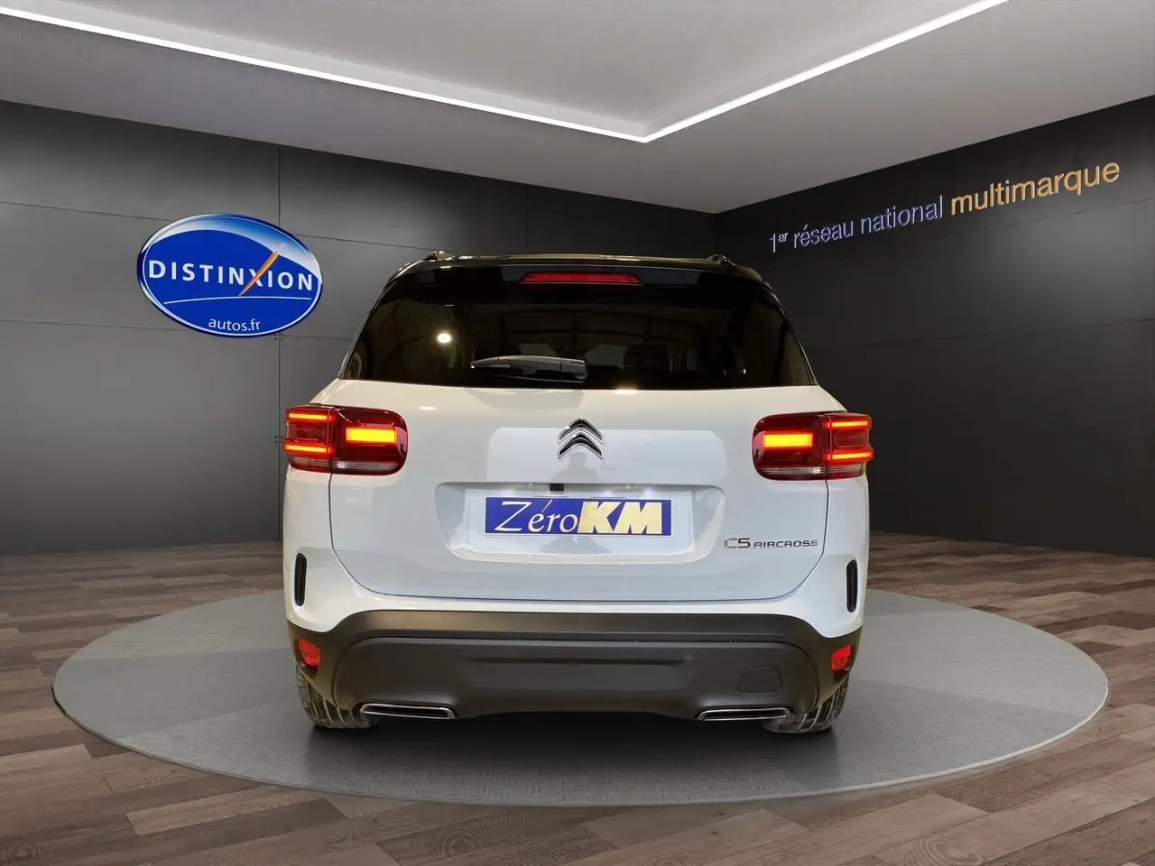 Vue arrière du Citroën C5 Aircross blanc et noir de 2024 avec feux allumés dans un showroom.