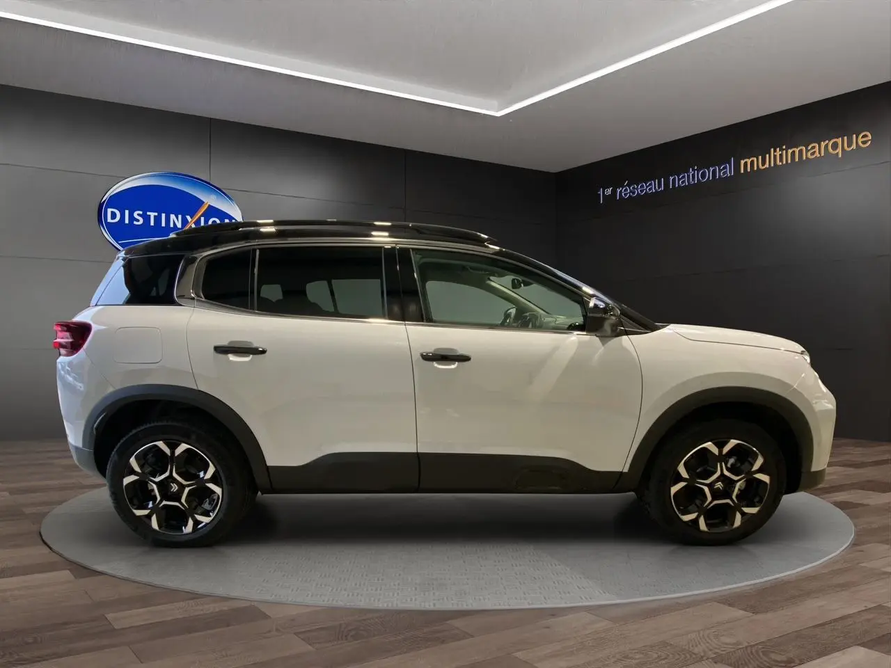 Profil côté droit du Citroën C5 Aircross 2024 blanc et noir avec jantes noires et toit contrasté en showroom.
