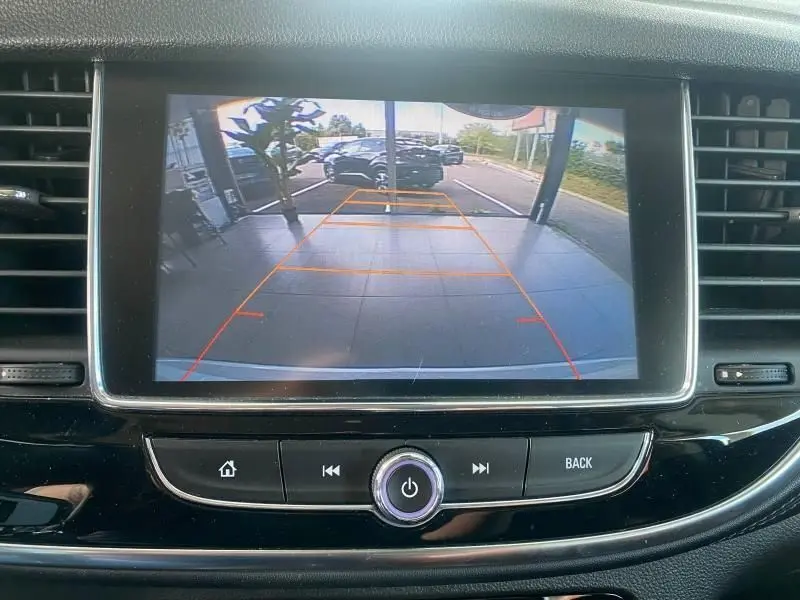 Écran central montrant la caméra de recul d'un Opel Mokka 2017, avec lignes de guidage orange sur un parking extérieur.
