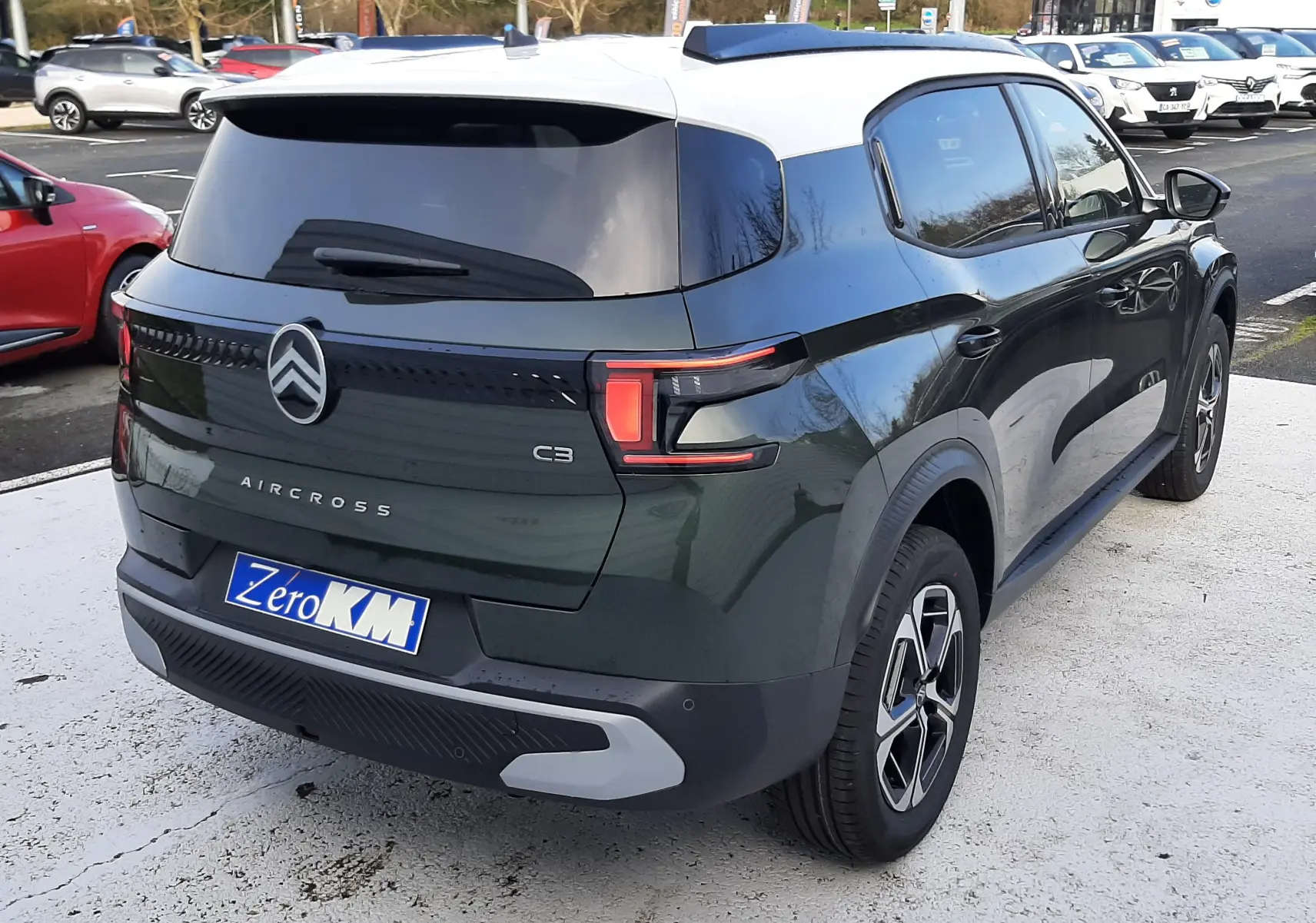 Vue 3/4 arrière droite d'un Citroën C3 Aircross hybride vert Montana avec toit blanc Opale, roues biton et feux LED.