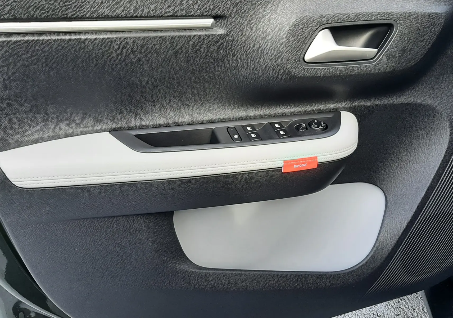 Détail de la porte côté conducteur du Citroën C3 Aircross hybride 2026, avec garniture noire et blanche et bouton rouge "be cool".