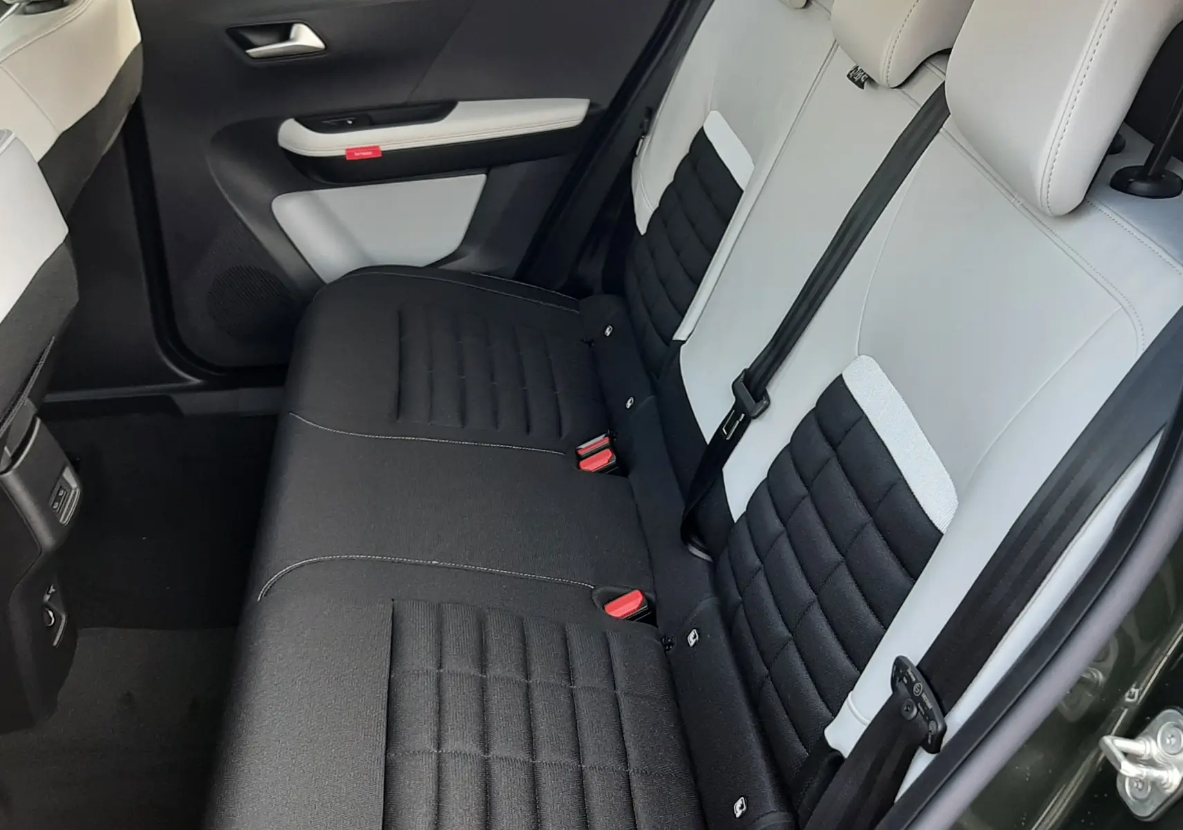 Vue intérieure côté arrière droit montrant les sièges arrière bicolores noir et blanc du Citroën C3 Aircross hybride 2026.