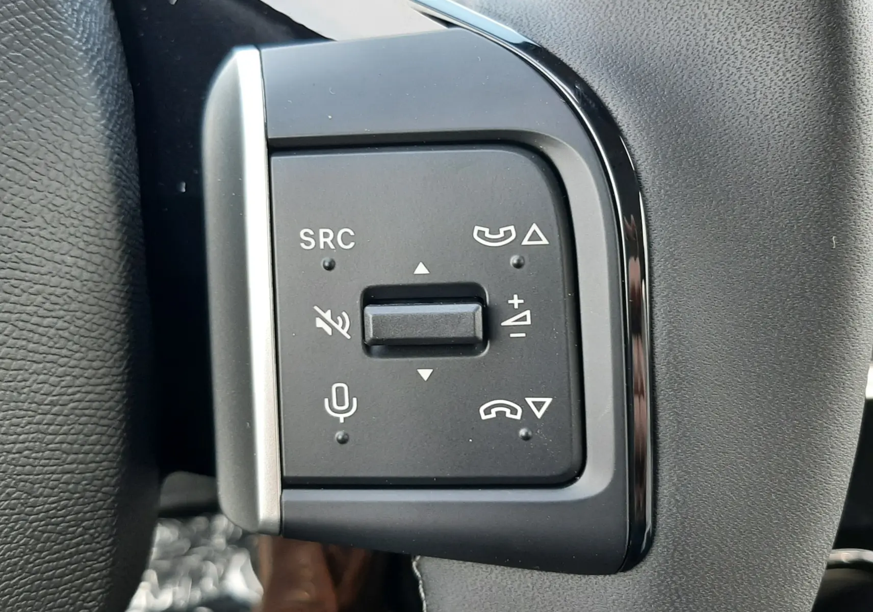 Gros plan sur les commandes multifonctions noires à gauche du volant gris du Citroën C3 Aircross hybride 2026.