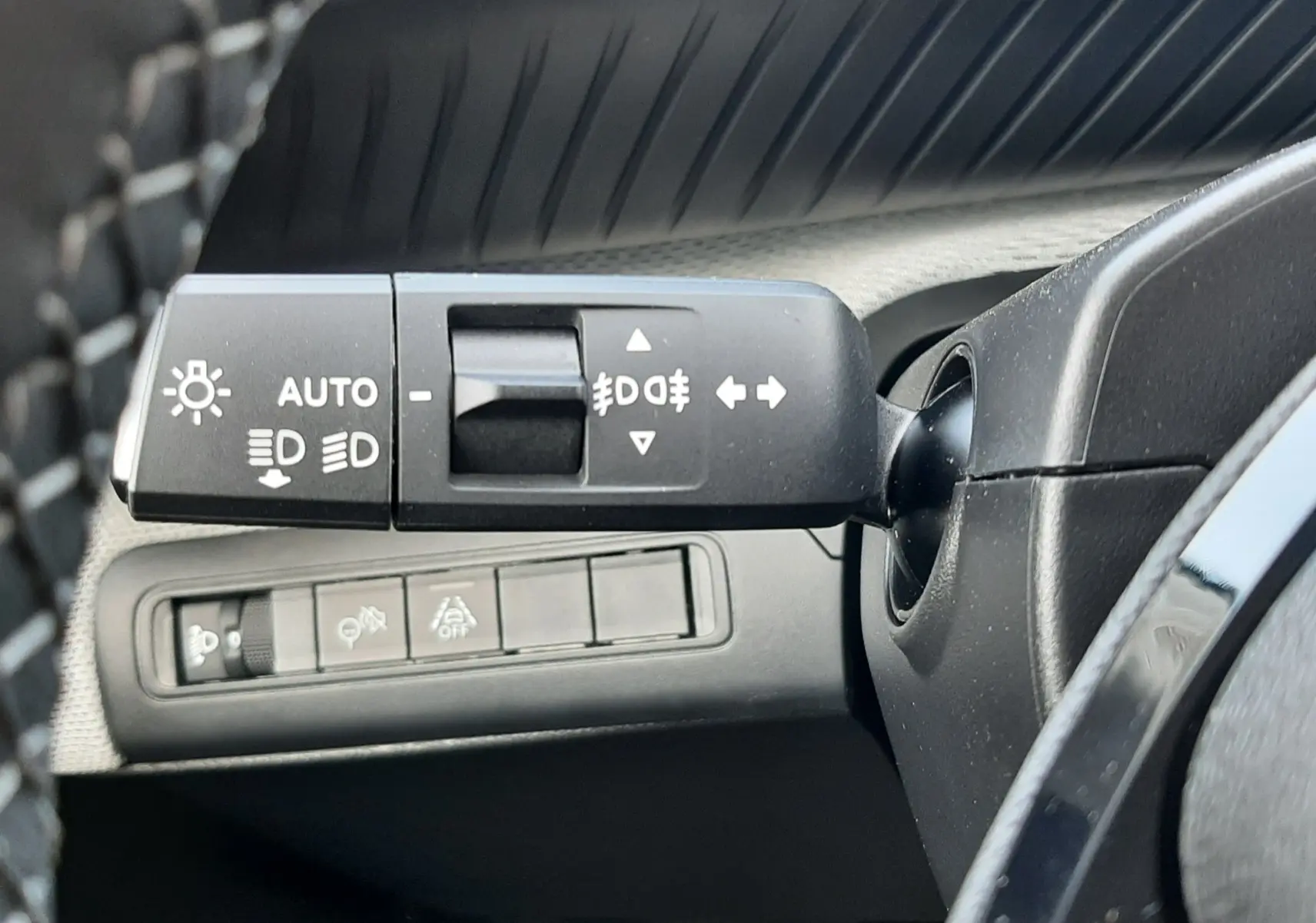 Gros plan sur la commande des feux et clignotants à gauche du volant dans l’habitacle noir du Citroën C3 Aircross hybride 2026.